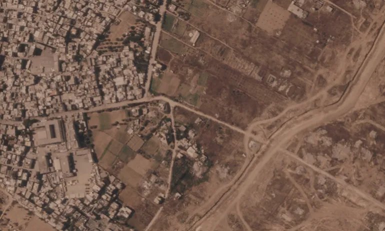 This satellite image from Planet Labs PBC shows a section of an earthen barrier being built by the Israeli military, right side of image moving top to bottom, in the central Gaza Strip, July 1, 2026. At left is the Maghazi refugee camp, and on the other side are homes demolished by the military. (Planet Labs PBC via AP)