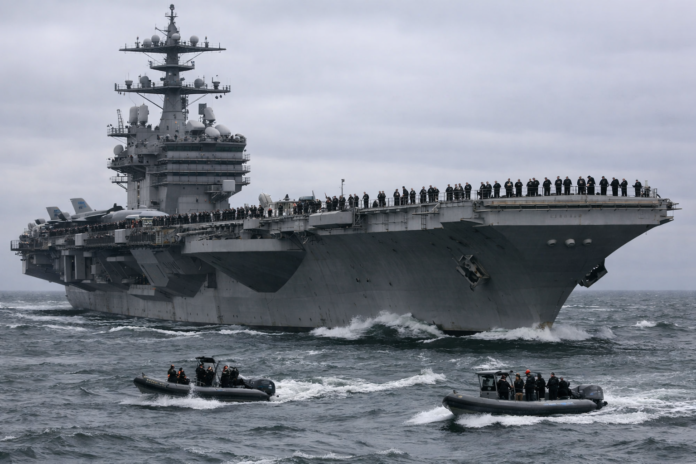 Aircraft carrier with sailors and escort boats at sea